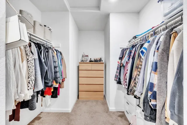 a view of walk in closet with clothes and shoes