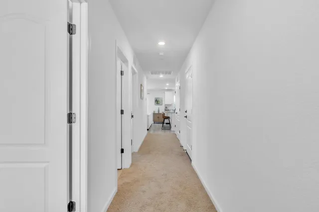 a view of a hallway with wooden floor and a bathroom