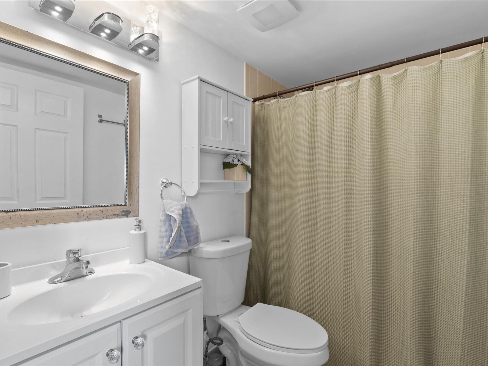 4025 Village Drive, Unit C Delray Beach, FL 33445 - Photo 18 of 32 a bathroom with a sink a toilet and shower curtain