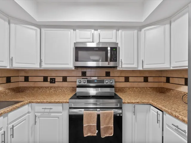 a kitchen with granite countertop white cabinets and a stove a oven with white countertops