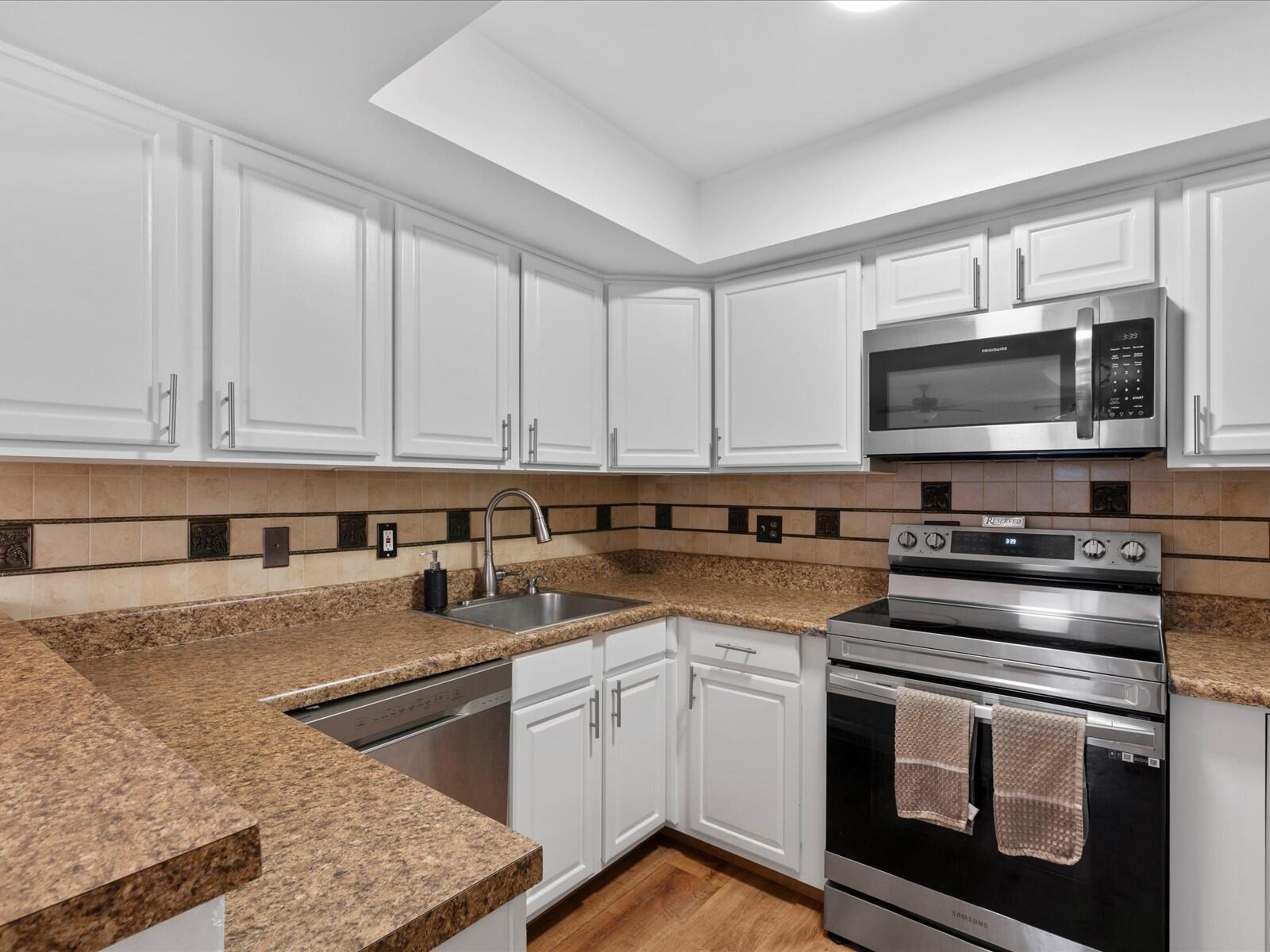 4025 Village Drive, Unit C Delray Beach, FL 33445 - Photo 6 of 32 a kitchen with stainless steel appliances granite countertop a stove a sink and a microwave