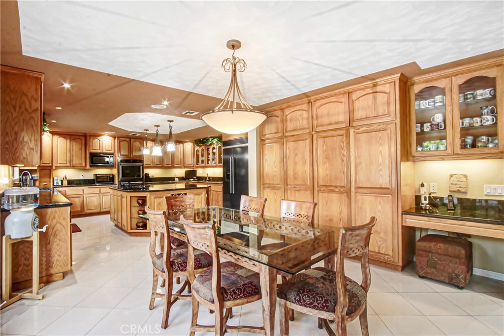 7954 Thoroughbred Street Rancho Cucamonga, CA 91701 - Photo 22 of 63 a dining room with stainless steel appliances kitchen island granite countertop a table and chairs