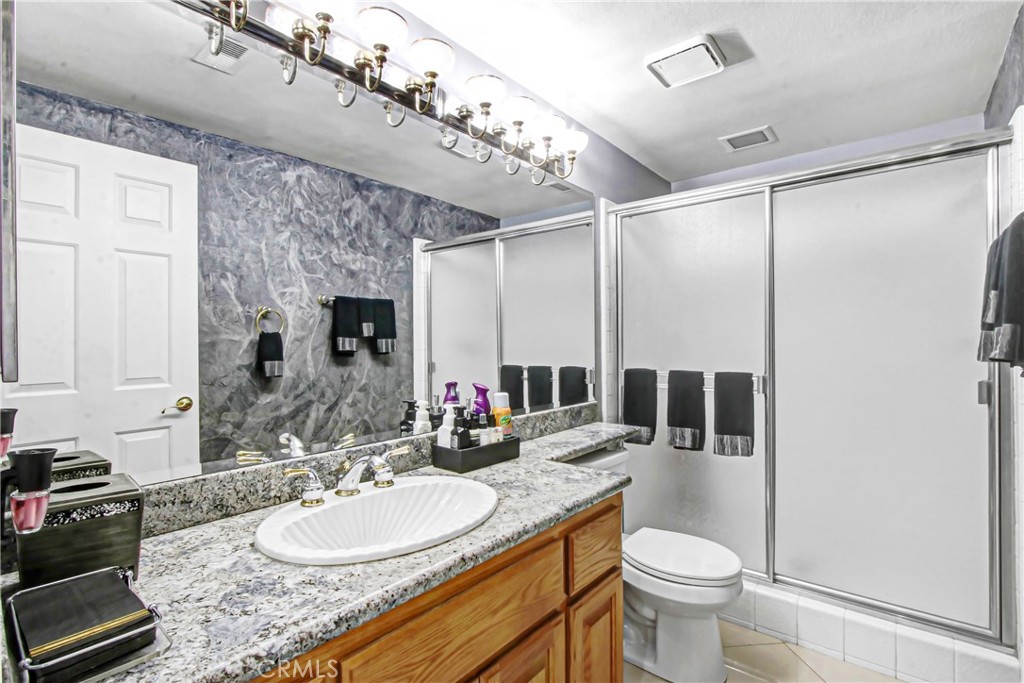 7954 Thoroughbred Street Rancho Cucamonga, CA 91701 - Photo 29 of 63 a bathroom with a granite countertop sink a toilet a mirror and shower