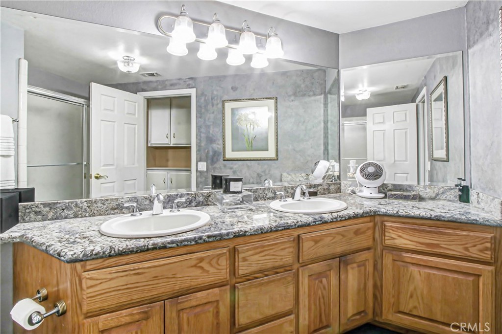 7954 Thoroughbred Street Rancho Cucamonga, CA 91701 - Photo 46 of 63 a bathroom with a granite countertop double vanity sink and mirror