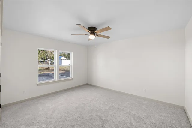 an empty room with fan and windows