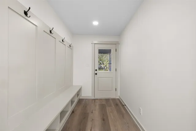 a view of a hallway with wooden floor and a bathroom