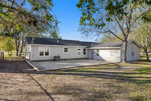 a view of a house with a yard and large tree