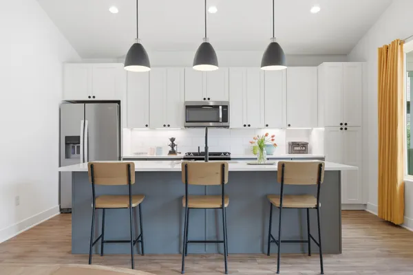 a kitchen with stainless steel appliances a dining table chairs and white cabinets