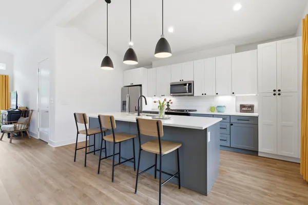 a kitchen with stainless steel appliances kitchen island granite countertop a sink a stove a dining table and chairs with wooden floor