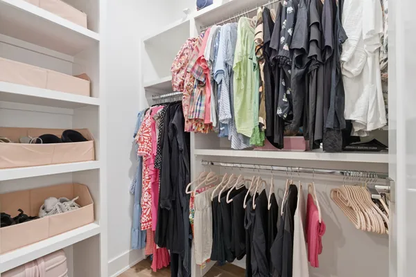 a view of walk in closet with clothes and shoes