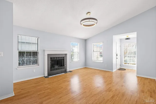 an empty room with windows fireplace and wooden floor