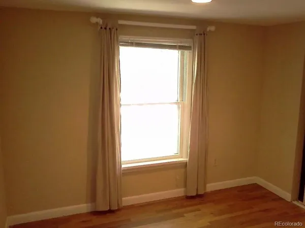 a view of an empty room and wooden floor and a window