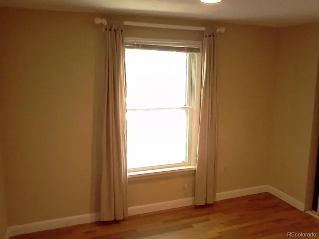 a view of an empty room and wooden floor and a window