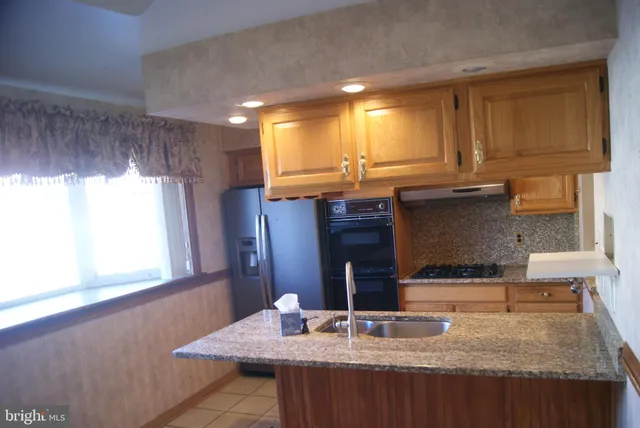 a kitchen with kitchen island granite countertop a sink cabinets and window