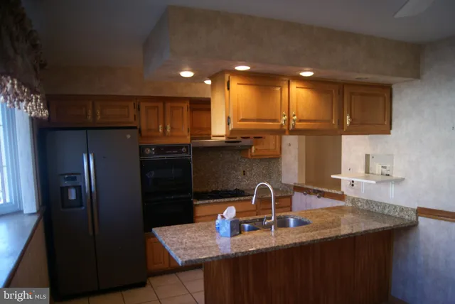 a kitchen with stainless steel appliances granite countertop a refrigerator a sink and a stove