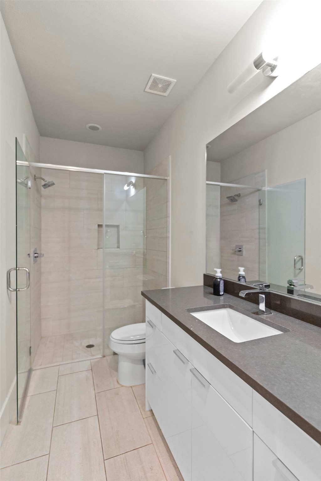 1613 Wheeler Avenue, Unit A Houston, TX 77004 - Photo 19 of 32 a bathroom with a granite countertop sink a toilet a mirror and shower