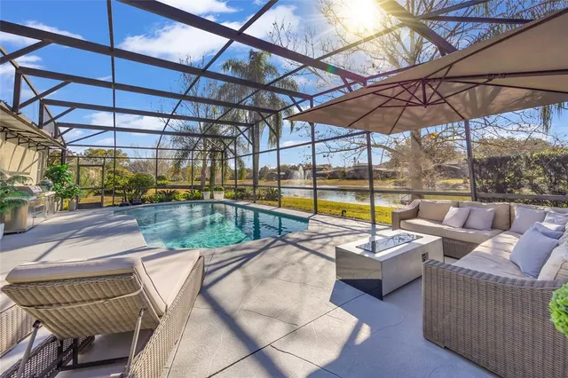 a view of a swimming pool with a couches and chairs under an umbrella