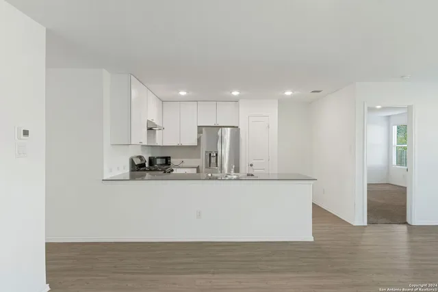 a large white kitchen with kitchen island sink and refrigerator