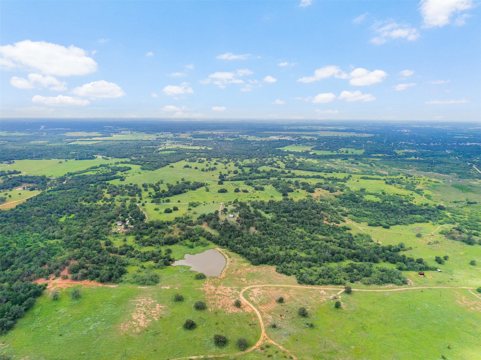 Tbd Lot 10 Tbd Road Luling, TX 78648 - Photo 8 of 10 Vast green acreage with mature trees and a serene pond, perfect for rural living or development.