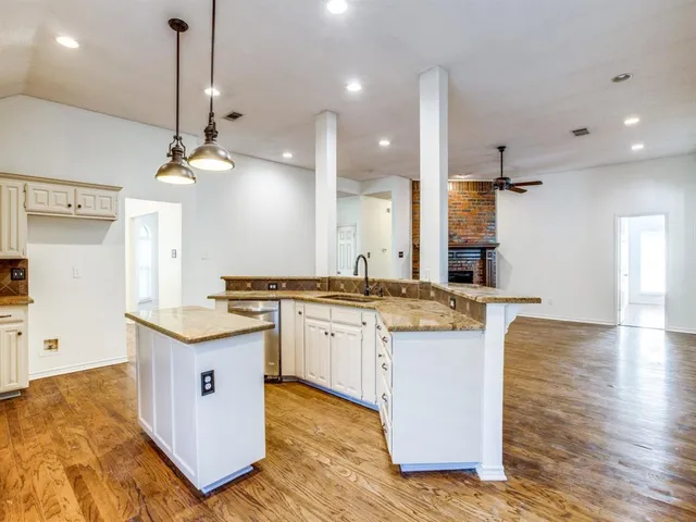 a large kitchen with granite countertop a sink and a stove top oven