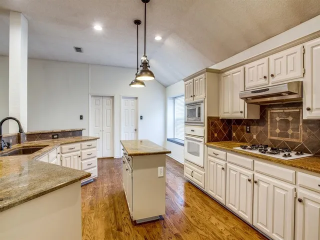 a kitchen with stainless steel appliances kitchen island granite countertop a sink a stove and cabinets