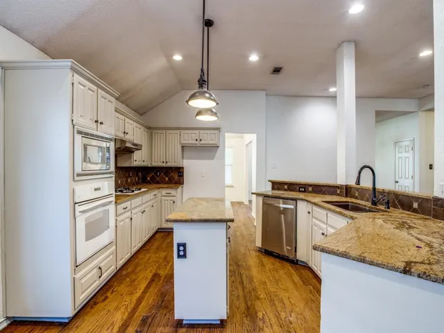 a large kitchen with stainless steel appliances kitchen island granite countertop a stove and a sink