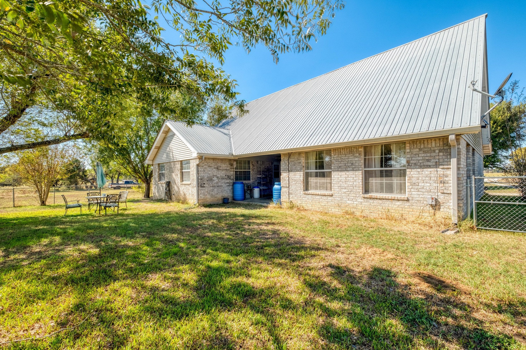 153 Pleasant Grove Road Elgin, TX 78621 - Photo 25 of 34 Rear view of house with a metal roof and brick siding