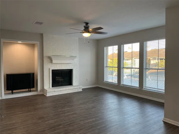 an empty room with wooden floor and chandelier fan