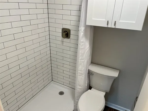 an empty room and a bathroom with a fan