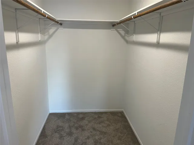 an empty room and a bathroom with a fan