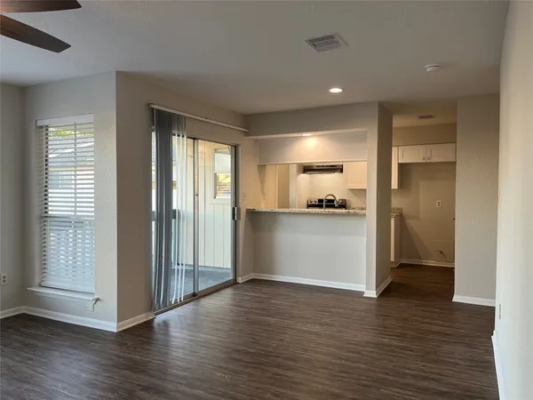 a view of a kitchen and an empty room with wooden floor and a window