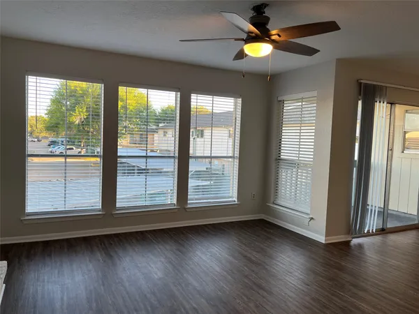 a view of an empty room with wooden floor and fan
