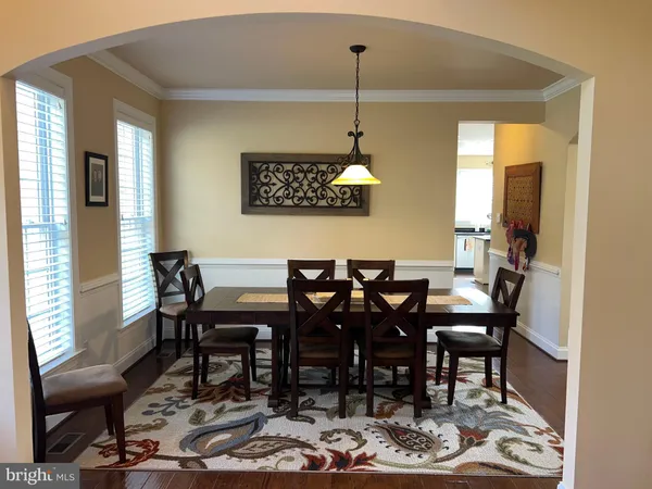 a view of a dining room and livingroom with furniture wooden floor a rug and a chandelier