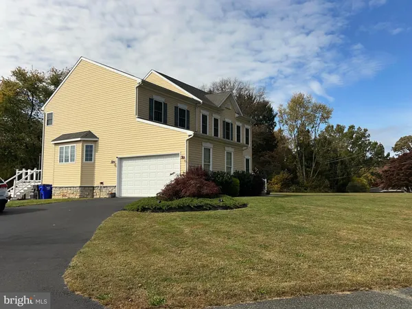 a front view of house with yard and trees in the background