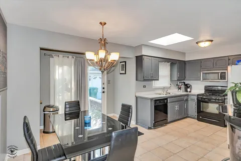 a open kitchen with stainless steel appliances granite countertop a stove top oven a sink dishwasher a dining table and chairs with wooden floor