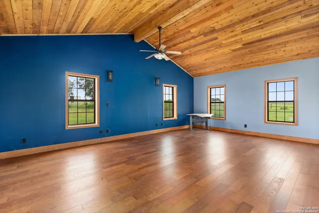 a view of empty room with wooden floor and fan