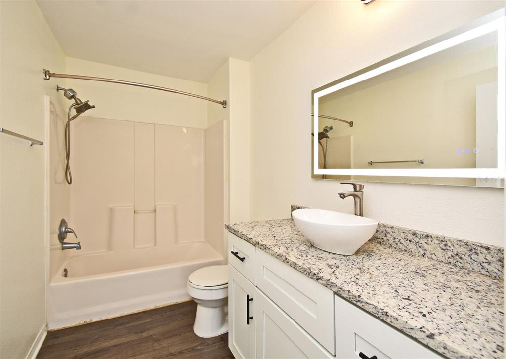 5467 Vineland Road, Unit 6308 Orlando, FL 32811 - Photo 13 of 39 a bathroom with a granite countertop sink a toilet and shower