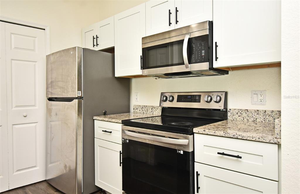 5467 Vineland Road, Unit 6308 Orlando, FL 32811 - Photo 26 of 39 a kitchen with stainless steel appliances granite countertop a stove microwave and refrigerator