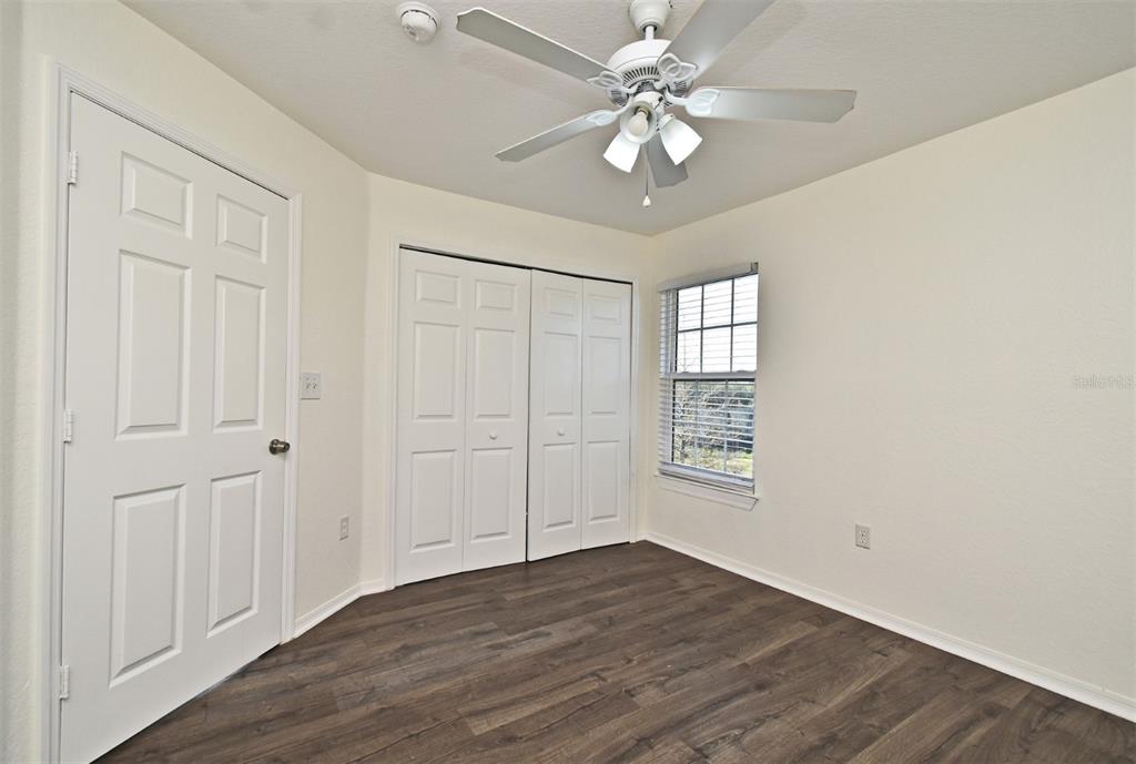 5467 Vineland Road, Unit 6308 Orlando, FL 32811 - Photo 9 of 39 an empty room with wooden floor ceiling fan and windows
