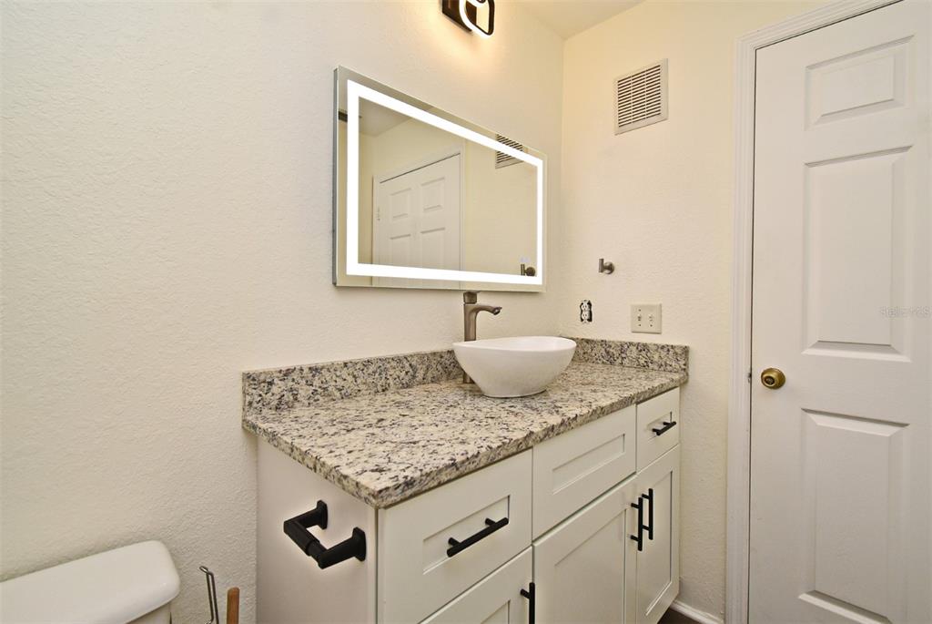 5467 Vineland Road, Unit 6308 Orlando, FL 32811 - Photo 10 of 39 a bathroom with a granite countertop sink and a mirror