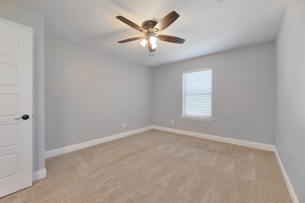 1713 Bronco Road Granbury, TX 76049 - Photo 16 of 23 Spacious room featuring neutral carpet flooring, light gray walls, a window with blinds, a ceiling fan with integrated lighting, and a white paneled door with black hardware