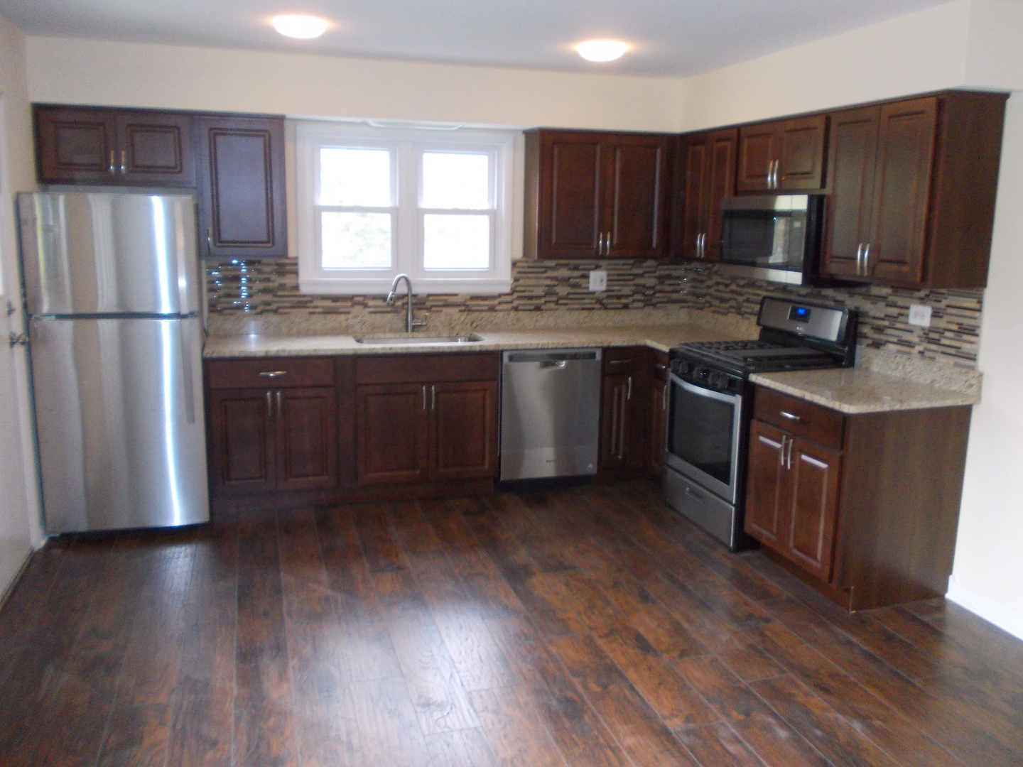 3435 Flossmoor Road Homewood, IL 60430 - Photo 5 of 13 a kitchen with granite countertop wooden floors stainless steel appliances a sink and a window