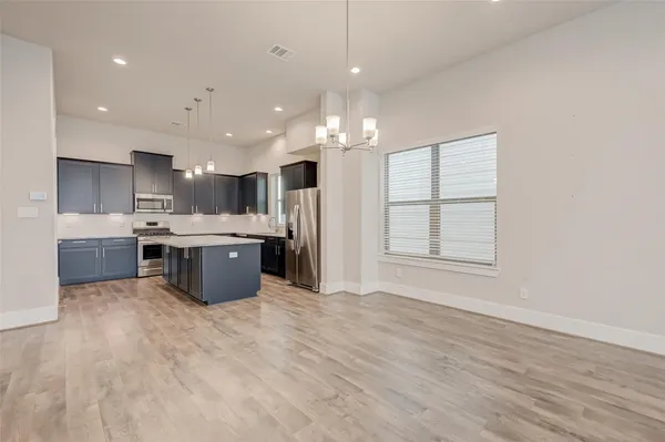 a large kitchen with stainless steel appliances kitchen island a large counter top a sink and a window