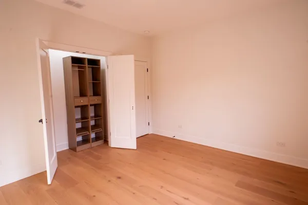 a view of an empty room with closet and wooden floor