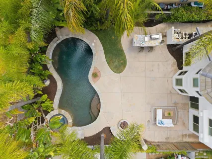an aerial view of a swimming pool with outdoor seating and yard