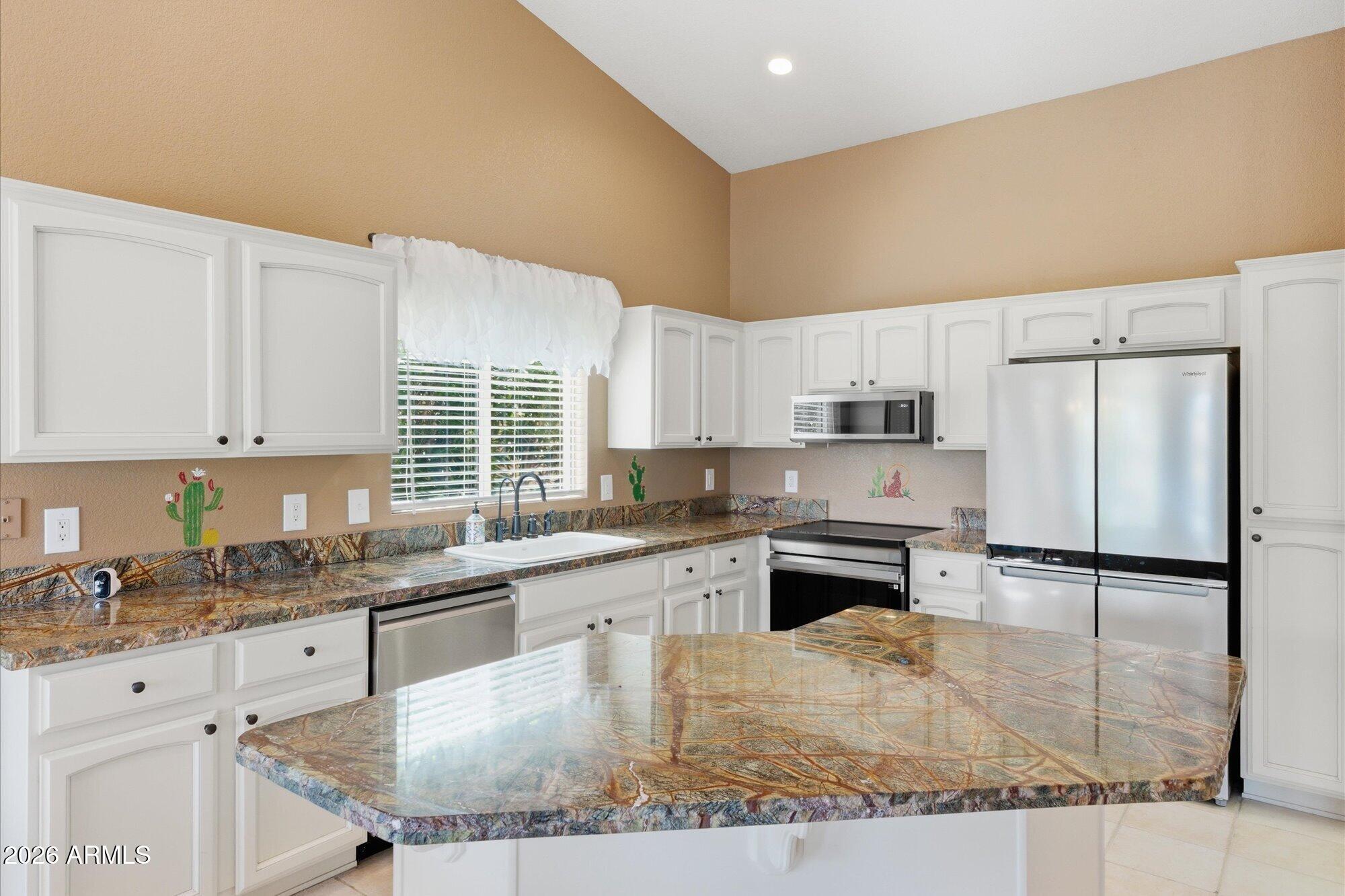 3895 North 150th Lane Goodyear, AZ 85395 - Photo 10 of 34 a kitchen with stainless steel appliances granite countertop a stove a sink a refrigerator and white cabinets