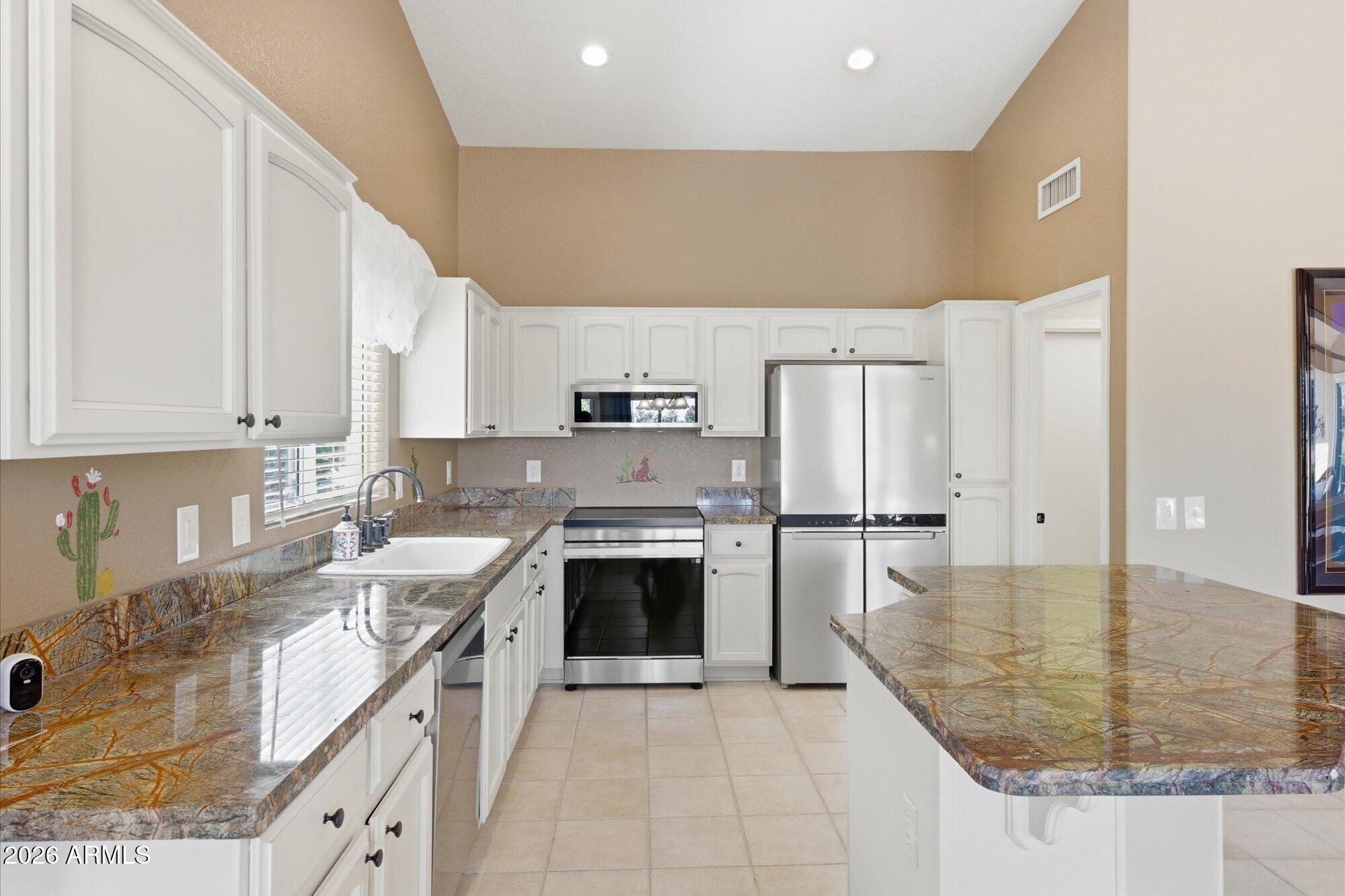 3895 North 150th Lane Goodyear, AZ 85395 - Photo 11 of 34 a large kitchen with stainless steel appliances granite countertop a sink stove and refrigerator