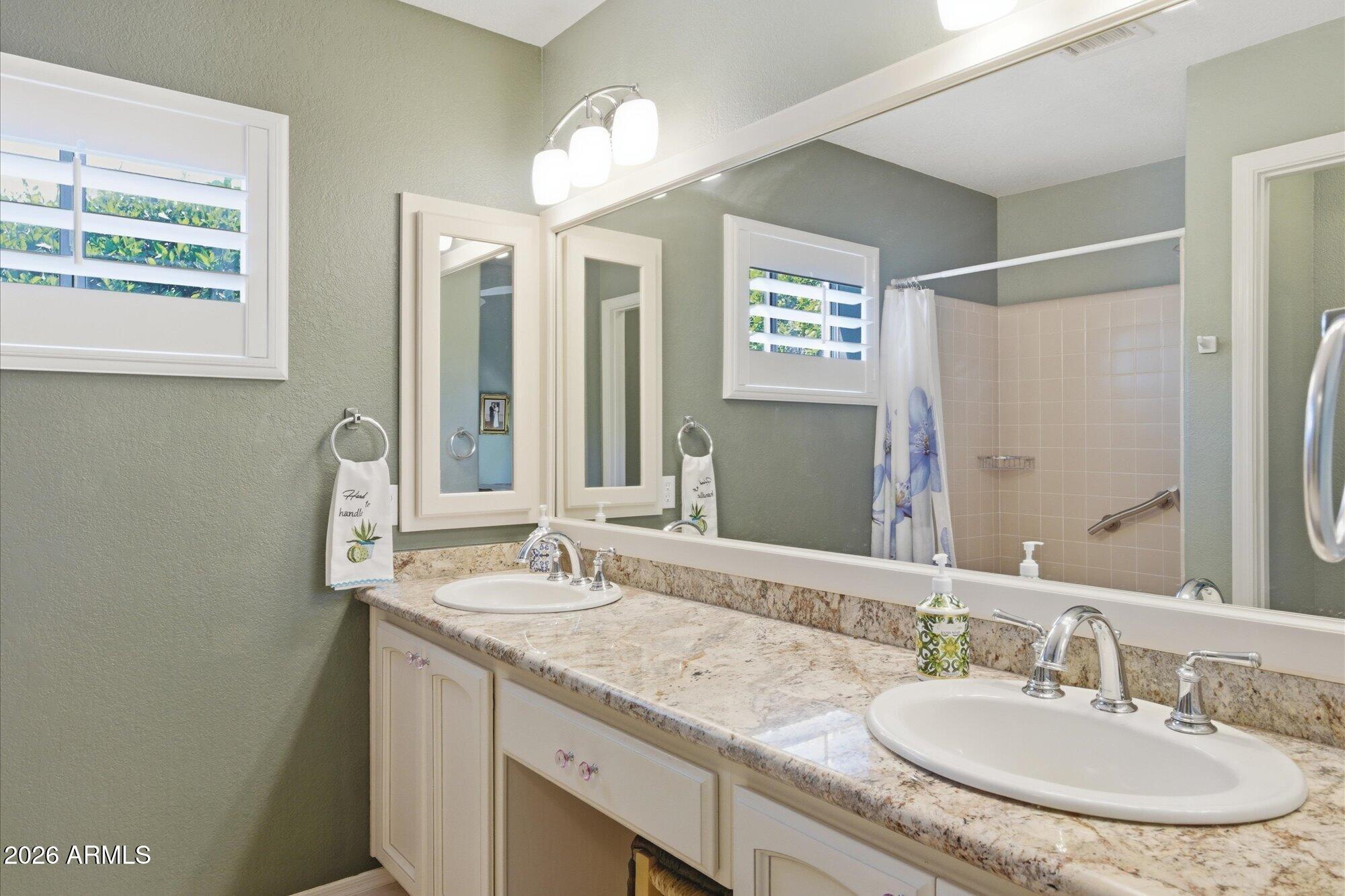 3895 North 150th Lane Goodyear, AZ 85395 - Photo 17 of 34 a bathroom with a granite countertop sink and a mirror