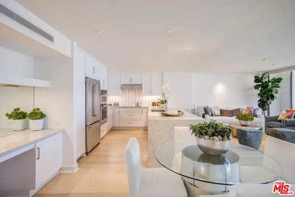 a room with lots of white furniture and potted plants