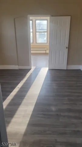 a view of an empty room with wooden floor and window
